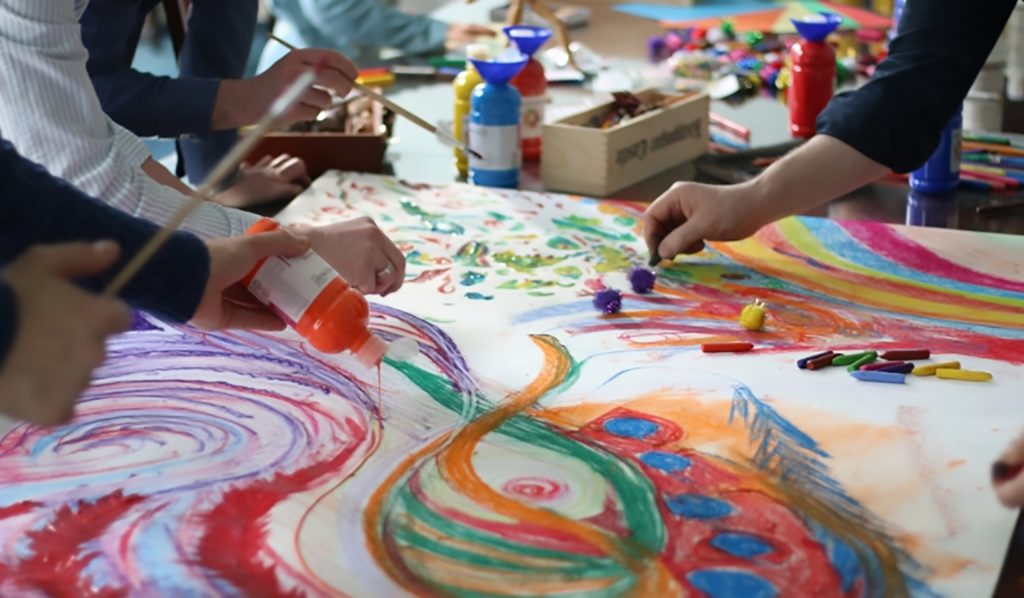 photo of students drawing and painting a group mural together.